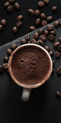 mug of coffee with coffee beans next to it